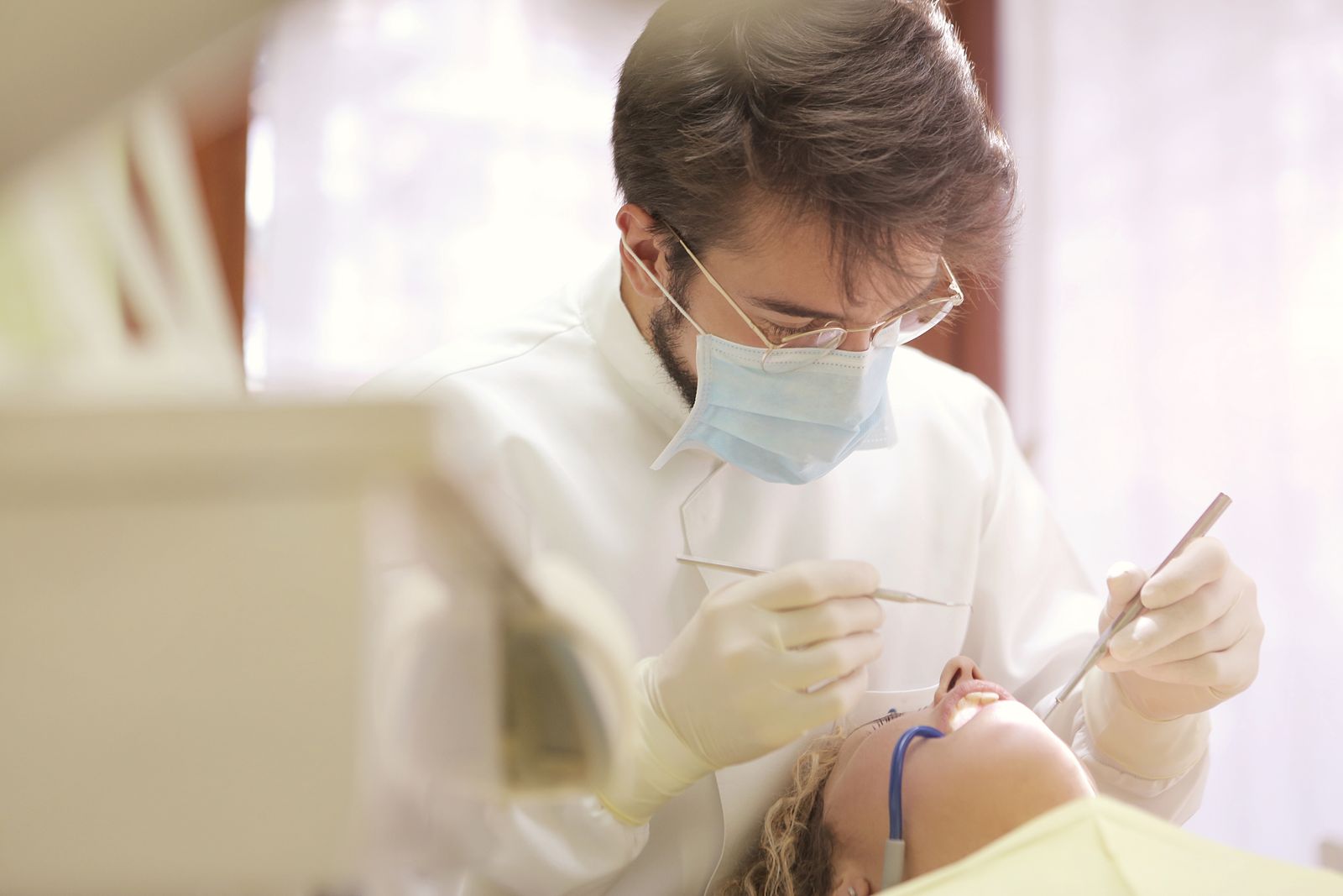 Dentist in a mask examining a patient with a mirror and probe