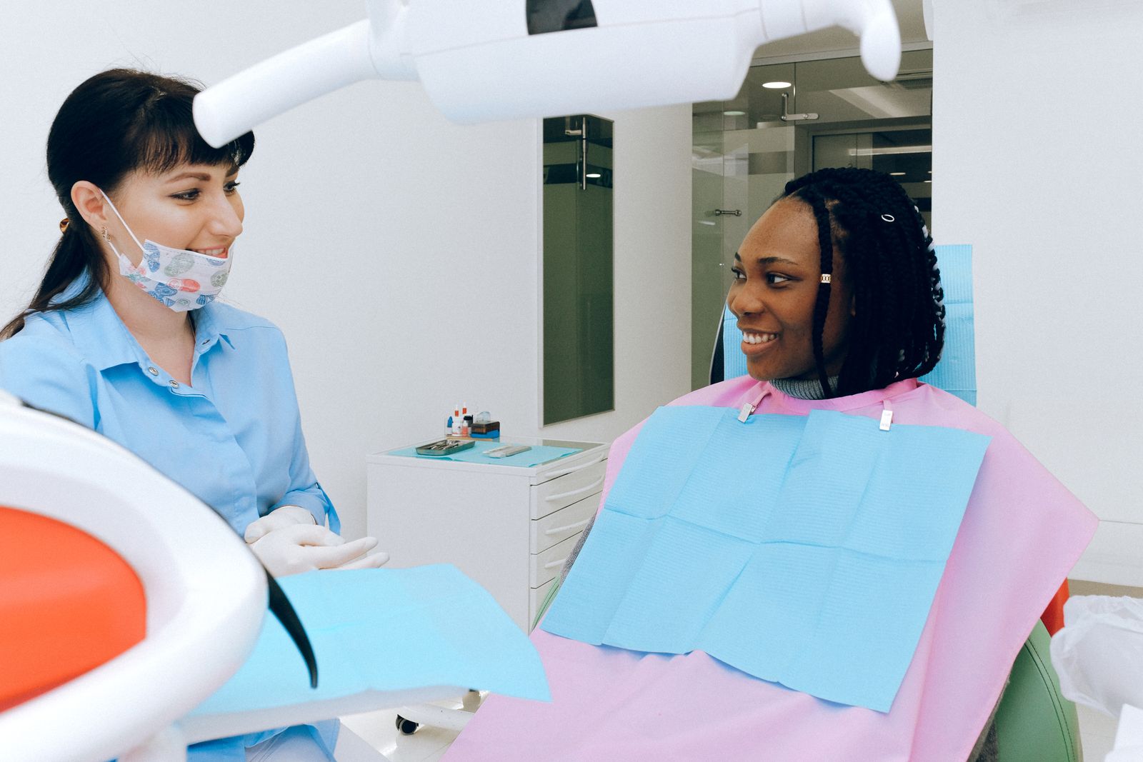 Dentist talking with a smiling patient in a standard dental treatment chair
